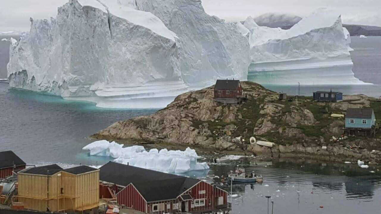 The Iceberg behind the village Innarsuit, on the Greenlandic west coast, Thursday July 12, 2018. 