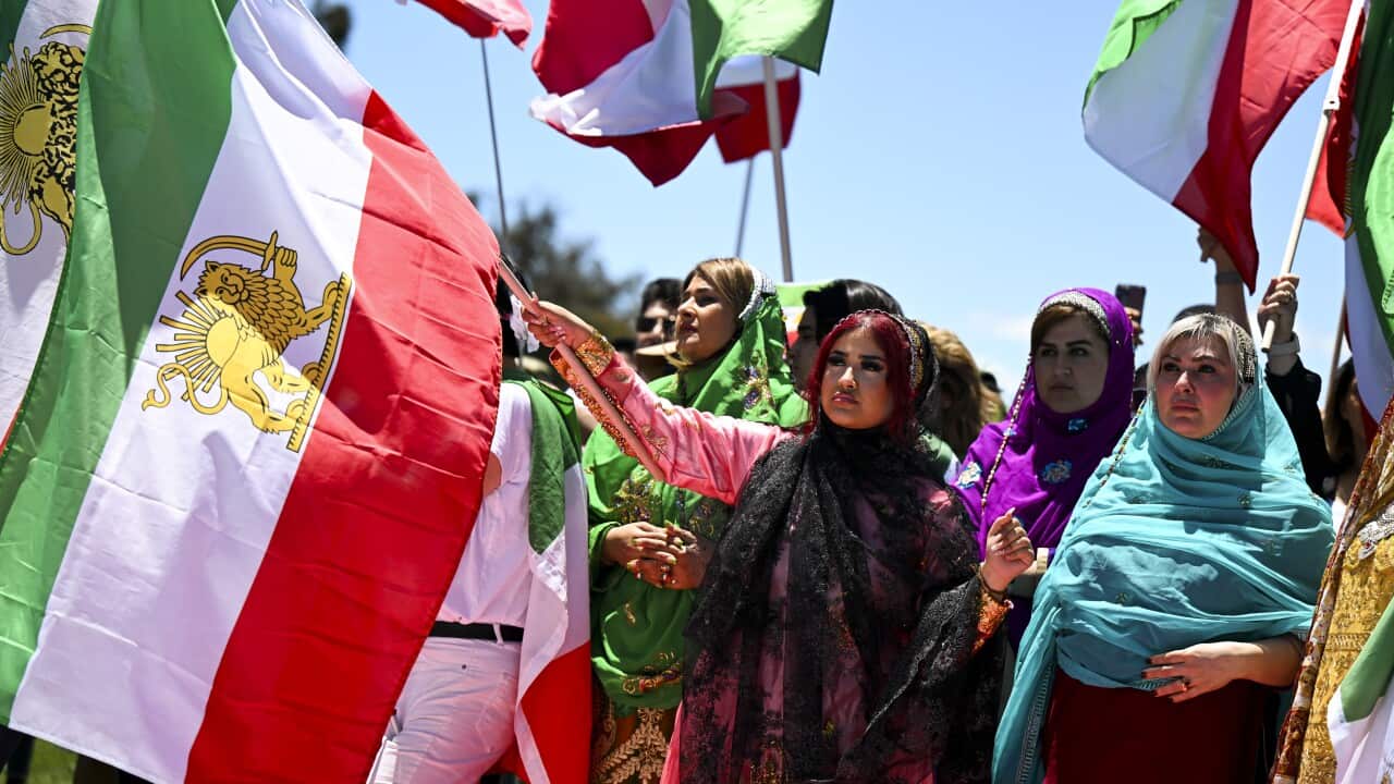 Women wearing hijabs holding flags of Iran.
