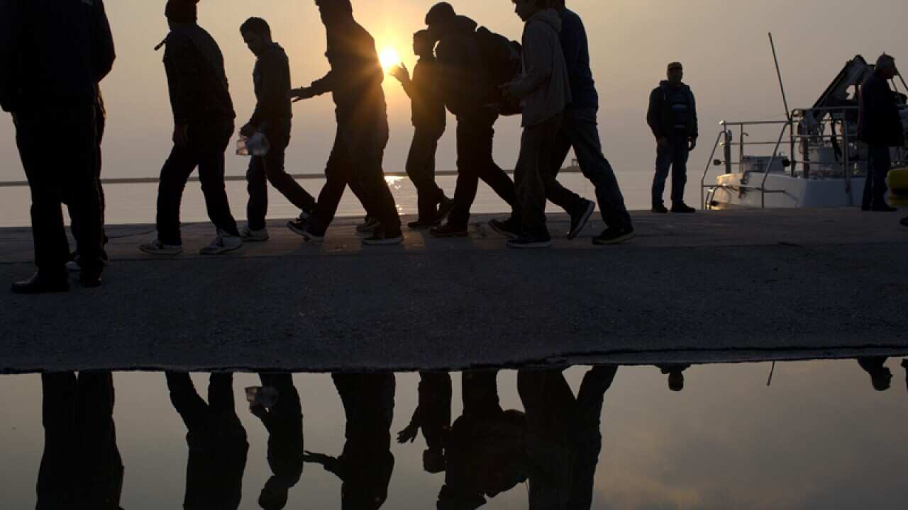 Migrants are reflected in a water puddle