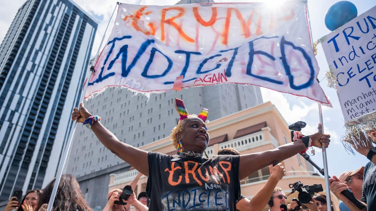 Protestors carrying a banner celebrating Donald Trump's indictment