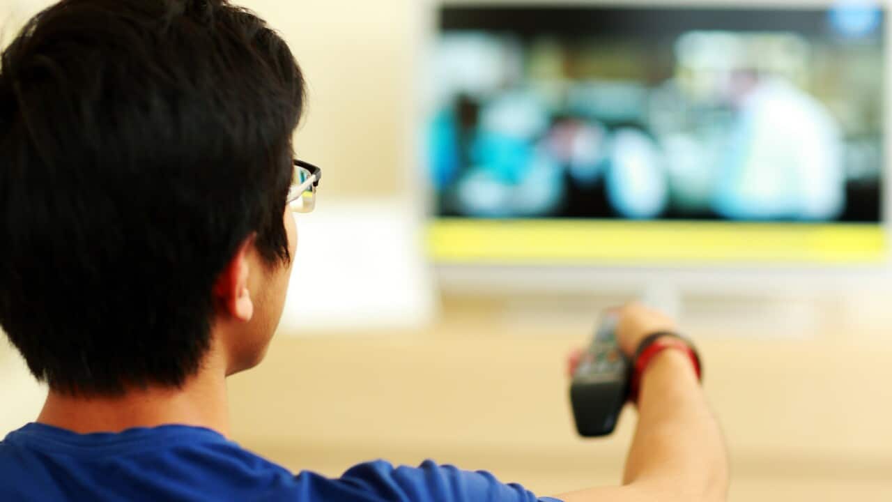 Back view portrait of a man watching tv at home in the living room