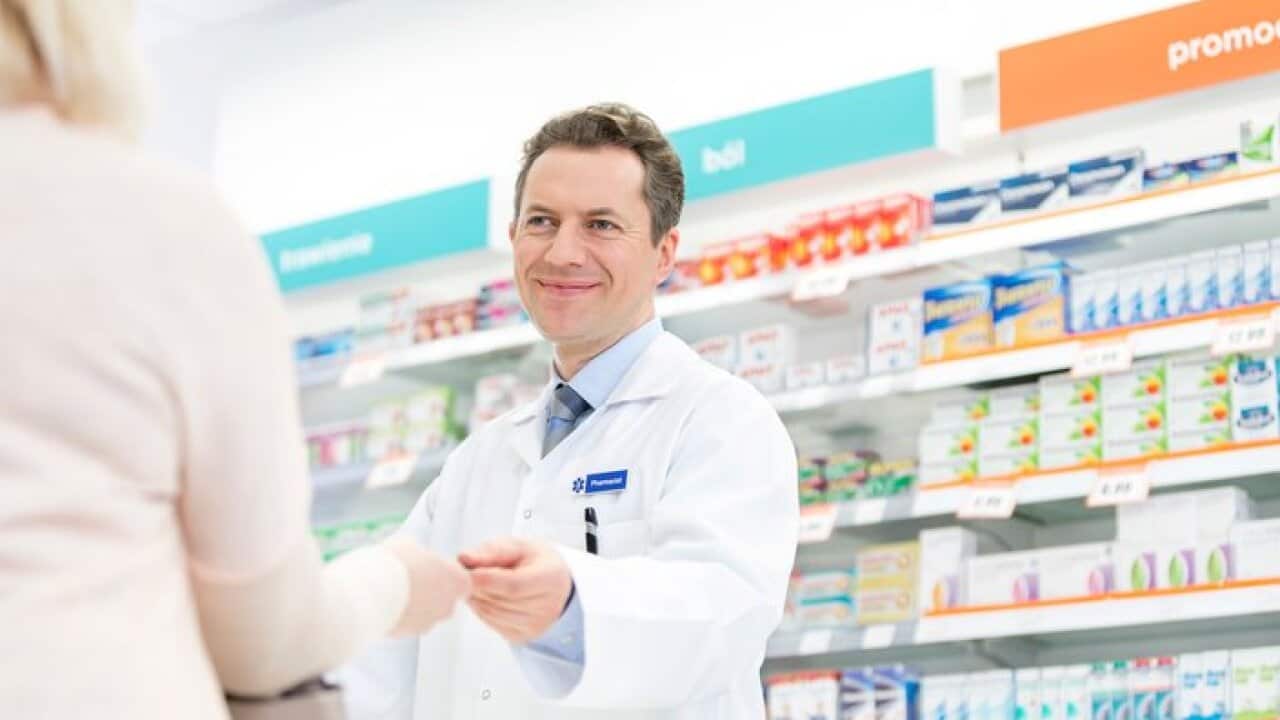 Smiling pharmacist assisting customer in pharmacy