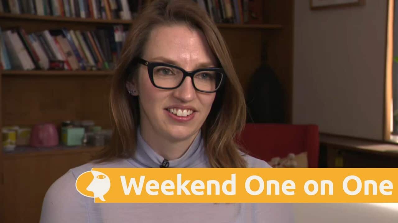 Dr Dara Conduit interviewed in front of a bookcase.