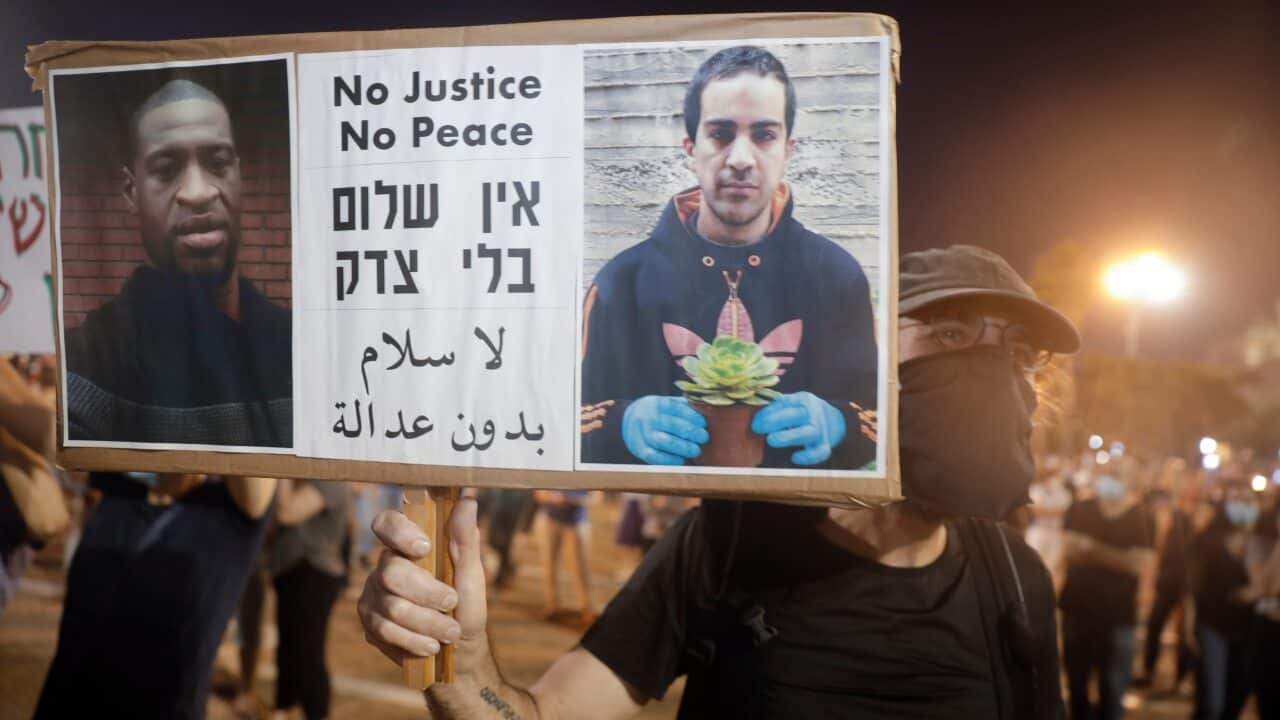 Protesters rally against Israel plans to annex parts of the West Bank, in Tel Aviv, Israel. On the right of the sign is a portrait of Eyad Hallaq.