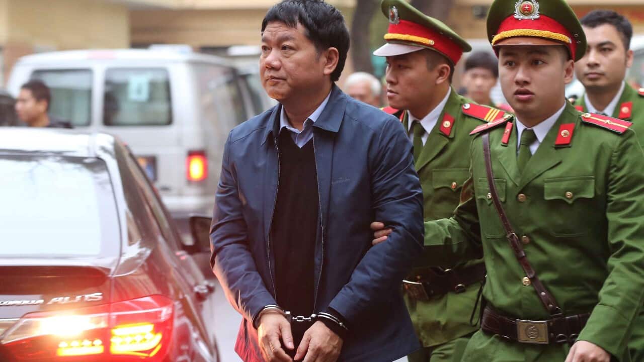 Vietnam's former Communist Party Politburo member and former chairman of PetroVietnam Dinh La Thang is escorted by police to the court in Hanoi
