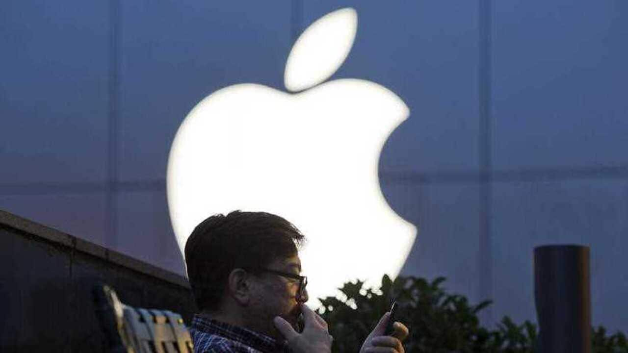 Man uses his mobile phone near an Apple store in Beijing, China