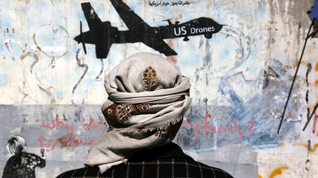 (File Image) A Yemeni stands in front of graffiti protesting US drone operations in Yemen in December 2016.