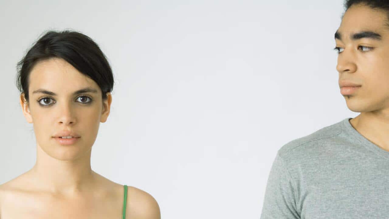 Young couple, woman looking at camera, man looking at woman