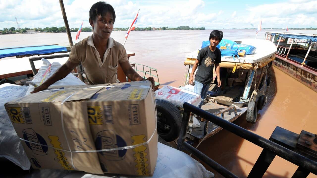 Thai workers load boxes on a boat at Nong Khai port in Nong Khai bound for Laos (PORNCHAI KITTIWONGSAKULAFP via Getty Images)