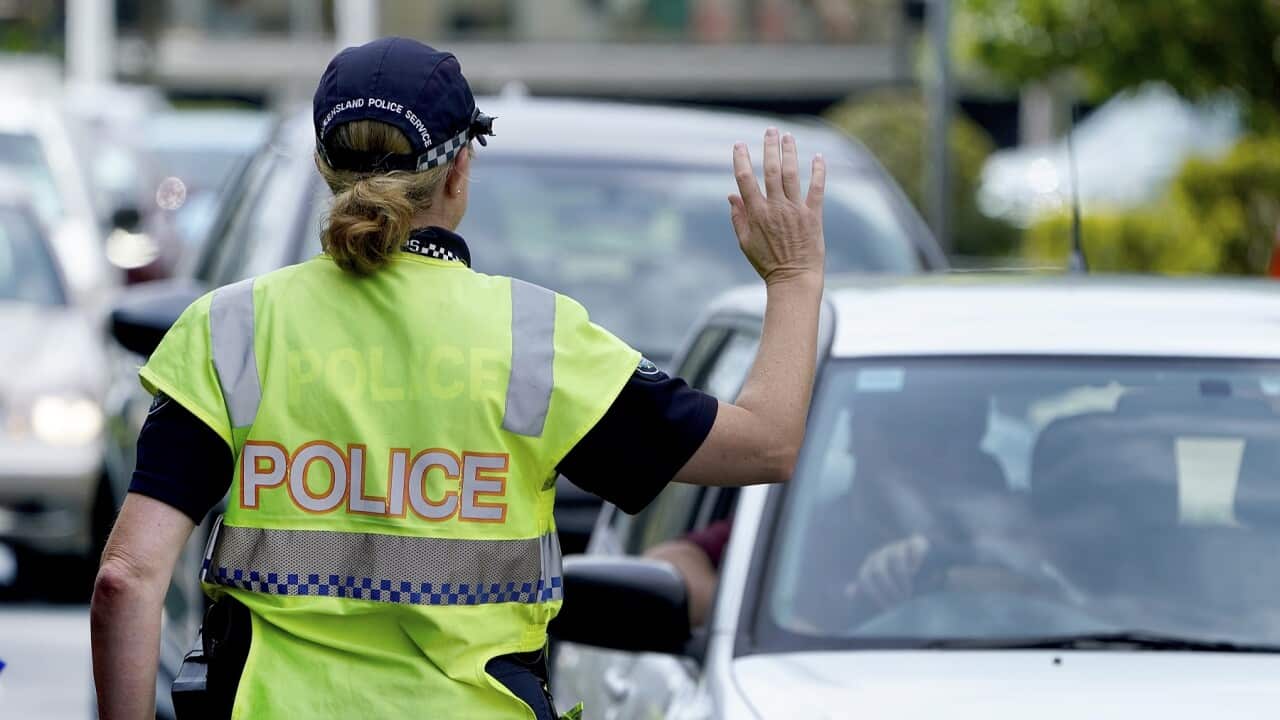 A police officer stops a driver at a checkpoint at Coolangatta on the Queensland - New South Wales border