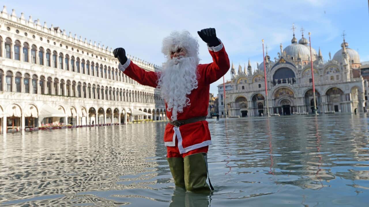 epa08088328 A man disguised as Santa Claus poses in San Marco square flooded by high water, Venice, Italy, 23 December 2019. The high tide reached 144 cm.  EPA/Andrea Merola