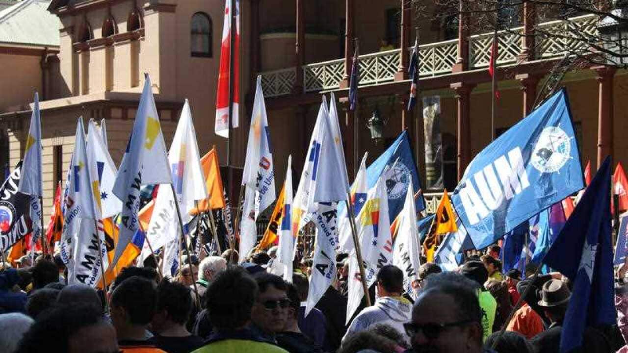 Banners are waved as around 1,000 unionists and activists protest outside the NSW State Parliament building in Sydney on July 31, 2015 to show their opposition to the free trade agreement signed between China and Australia. (AAP)
