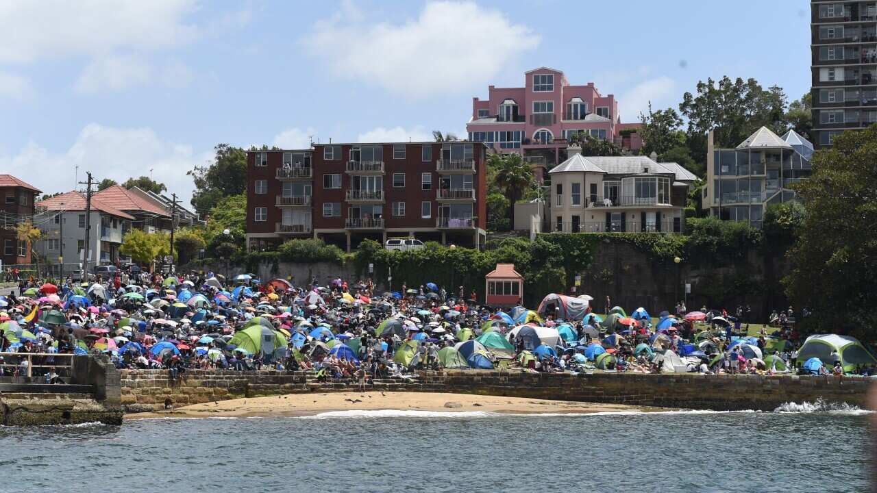 Thousands of New Year's Eve revellers take up their positions early on the Sydney Harbour foreshore at MacMahons Point. (AAP)