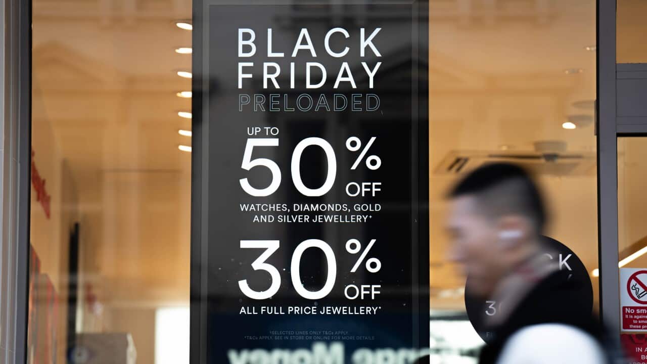 A person walking past a sign that sayd Black Friday preloaded up to 50 per cent off.