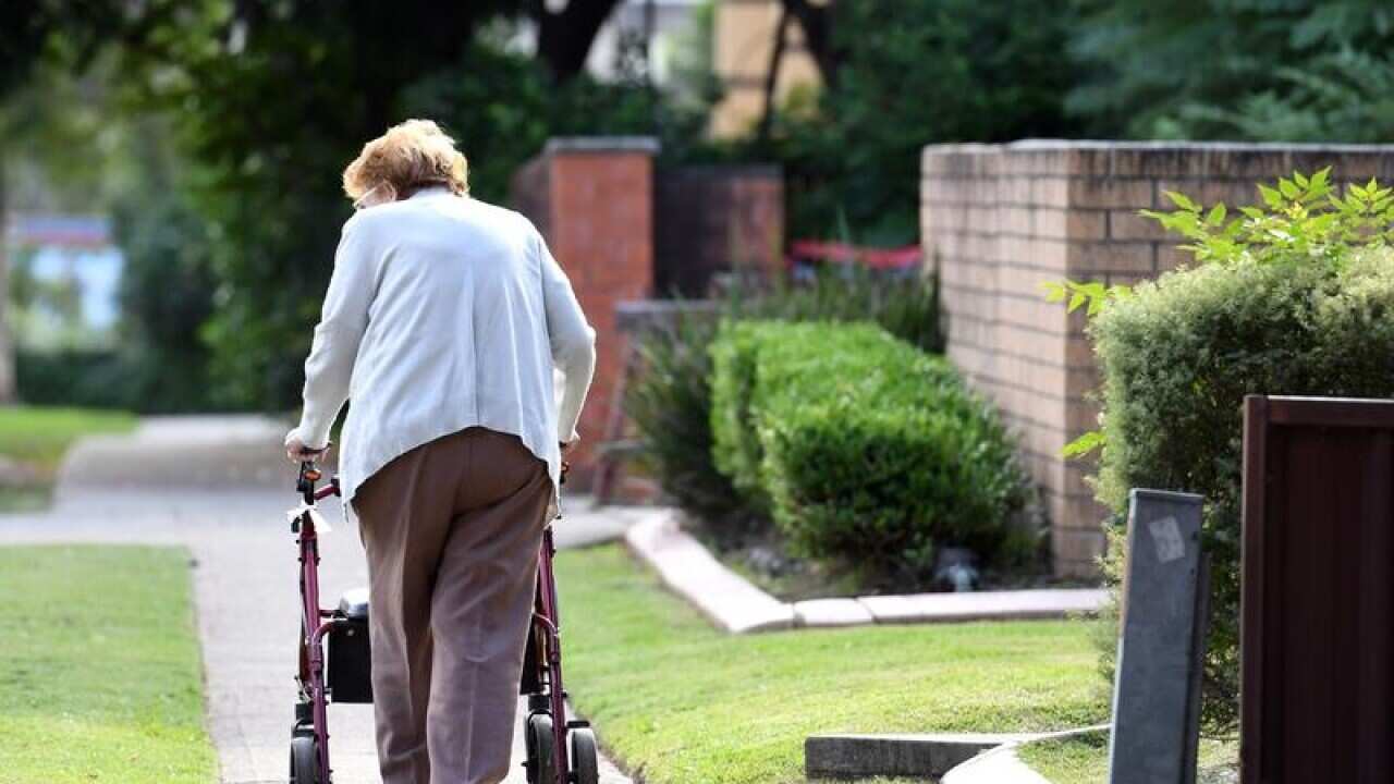 An elderly woman uses a mobility walker