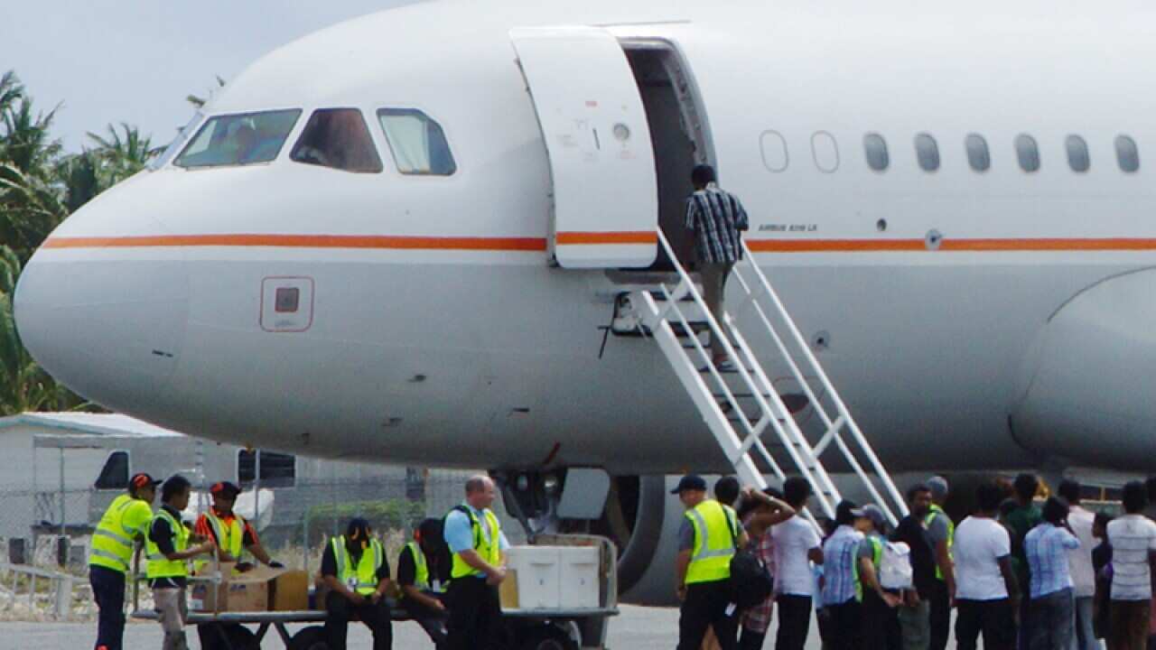 group of asylum seekers get on board an airplane at Cocos Island