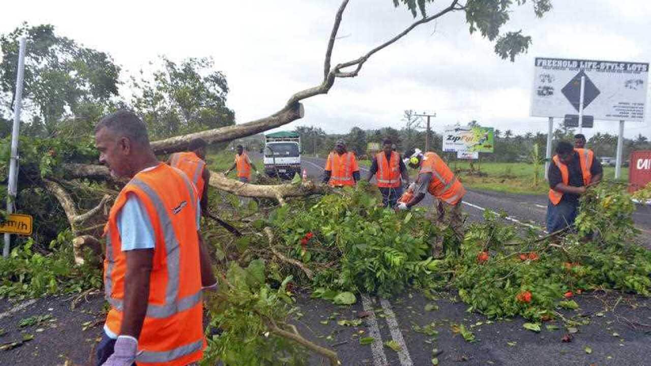 Road workers remove a fallen tree blocking a road near Lami, Fiji, Sunday, Feb. 21, 2016, after cyclone Winston ripped through the country.