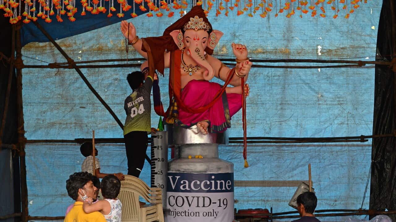 Devotees prepare to cover an eco-friendly papier-mache idol of the Hindu god Ganesha placed on a giant mock vial of the Covid-19 coronavirus vaccine