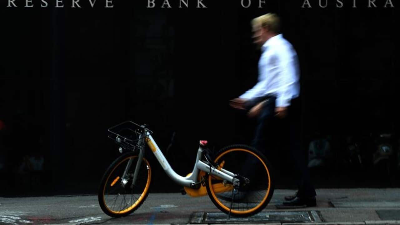 A man walks past a share bike that is in front of the RBA building.