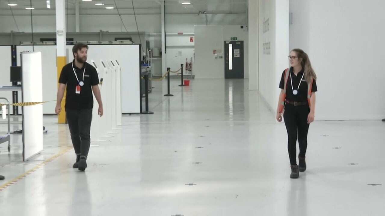 Factory workers wearing the social distancing device