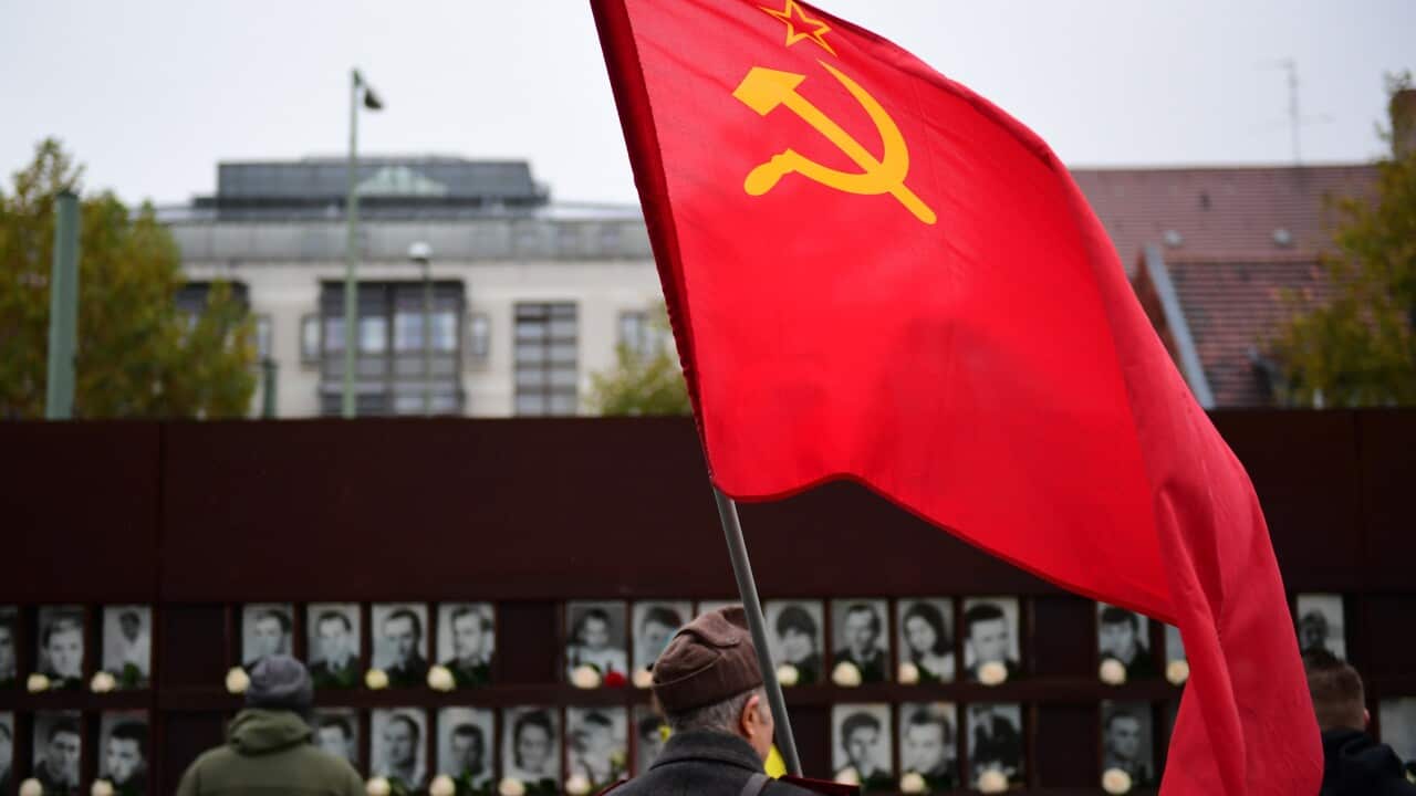 A man in a uniform with a soviet flag after the end of the official celebrations of the 30th anniversary of the fall of the Berlin Wall 