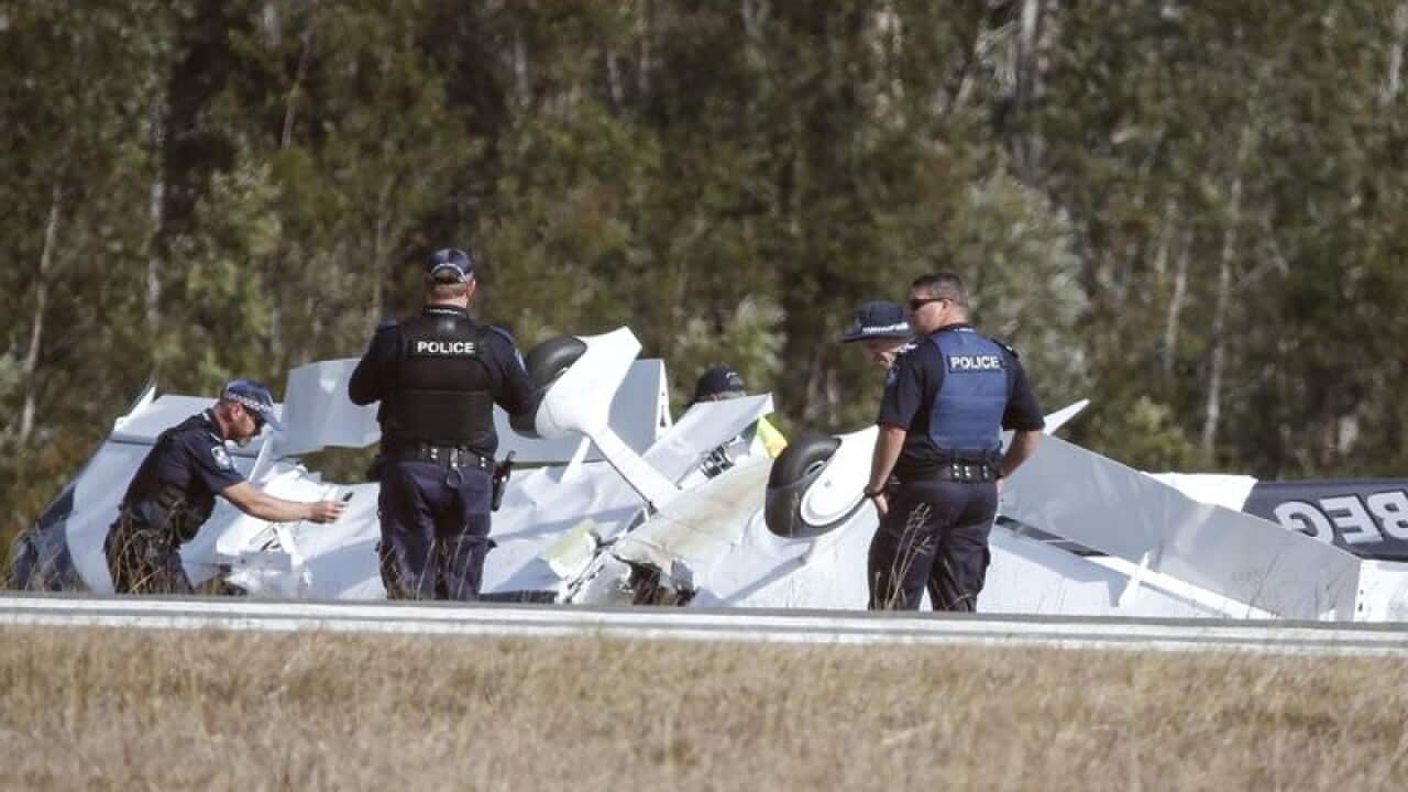 Police investigators examine the scene of a light plane crash