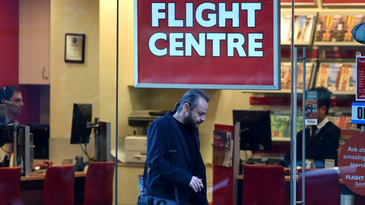 A pedestrian walks past a Flight Centre office