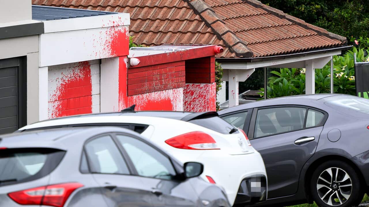 A white house and garage are splattered in red paint.