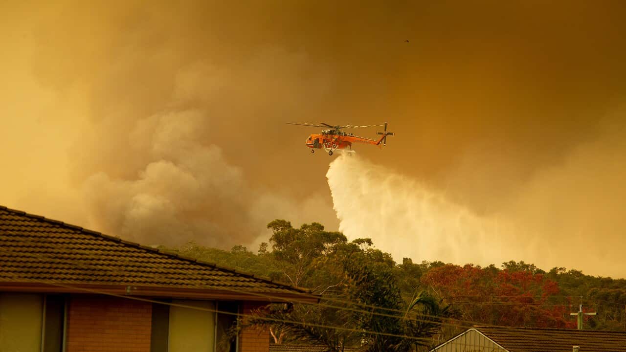 An Aircrane water bombing helicopter drops water on a bushfires in Harrington, 335km north east of Sydney