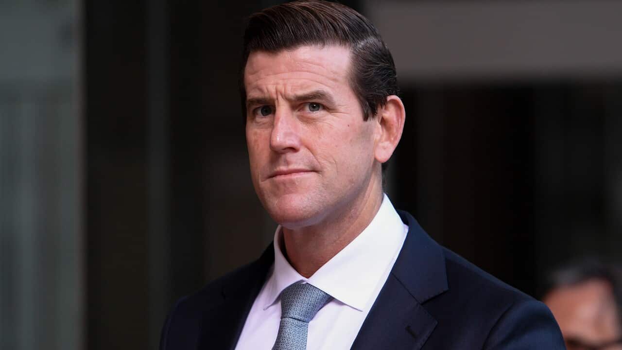 A man in a navy suit, white shirt and blue tie.