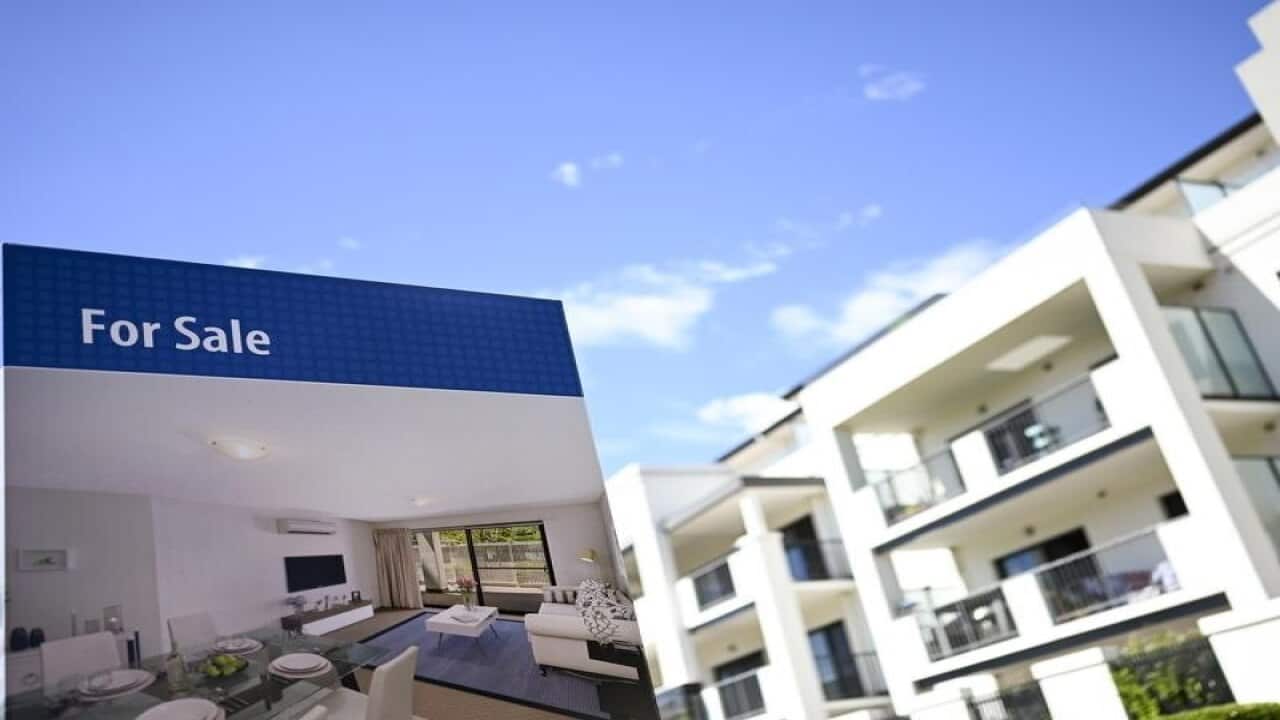 A real estate advertising board is seen next to a house in Canberra,