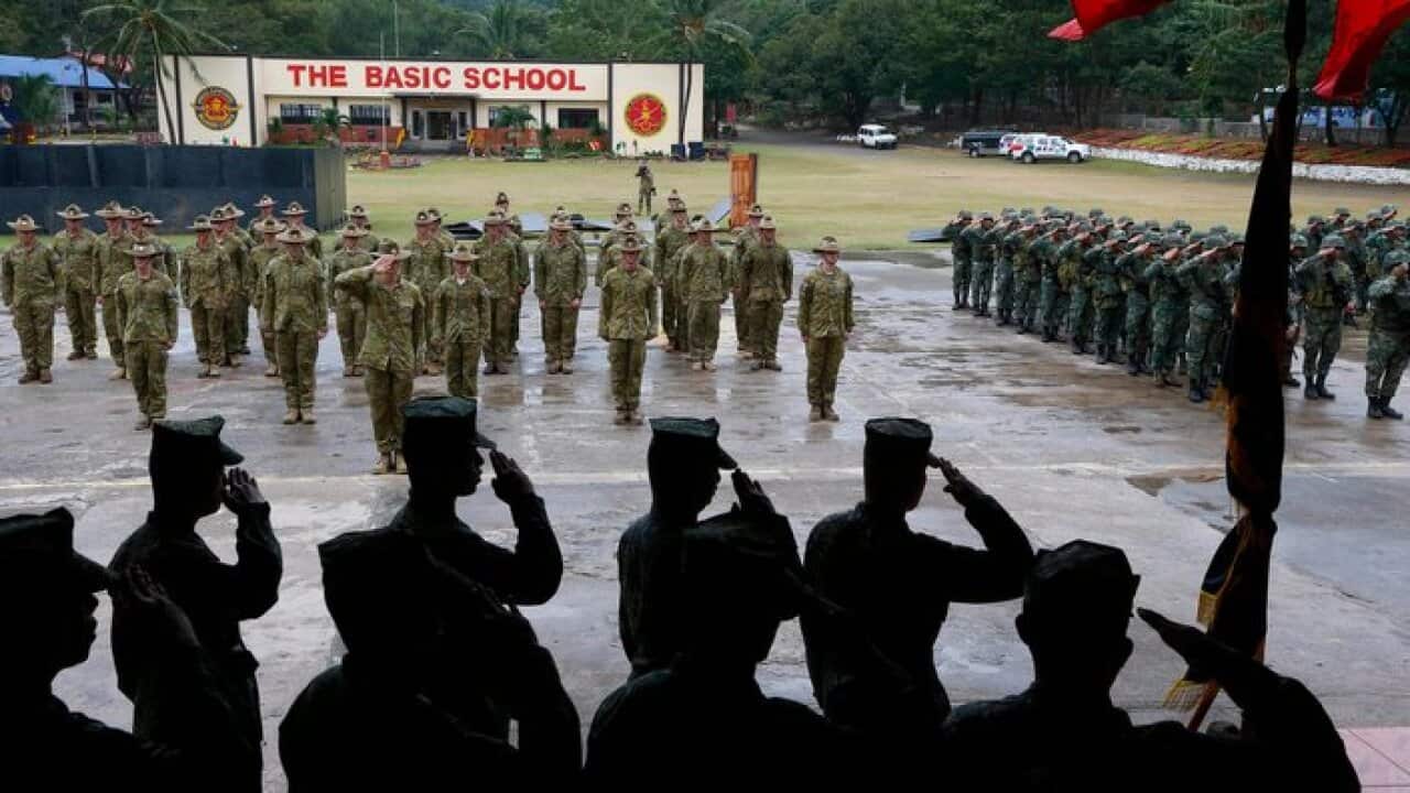 Australian Defense Forces and Philippine Marines salute as their respective national anthems is played.