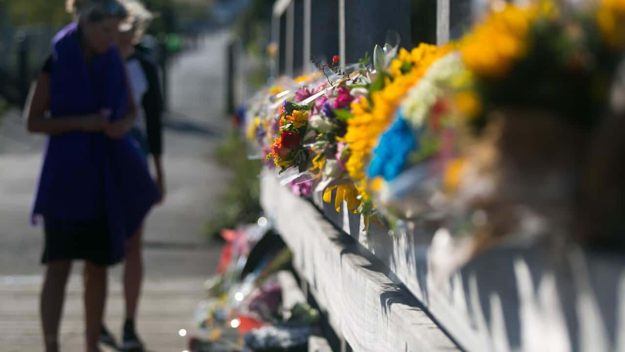 A resident pays respects near a floral tribute at the footbridge that connects the Airshow car park, for those who lost their lives. (PA)