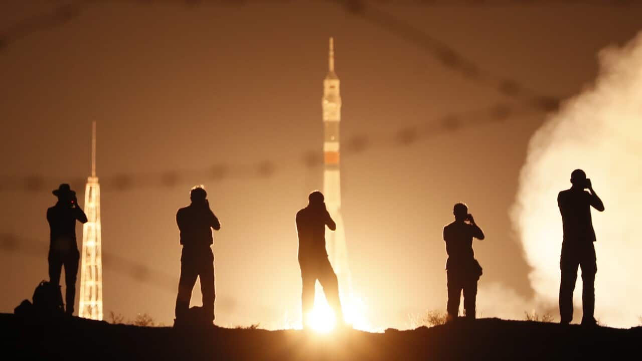 Media take photos as a spacecraft launches with members of the International Space Station expedition onboard.