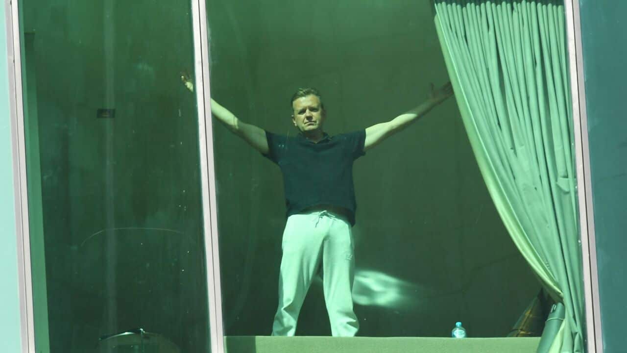 A man gestures from a hotel room at the Melbourne hotel where he is quarantined