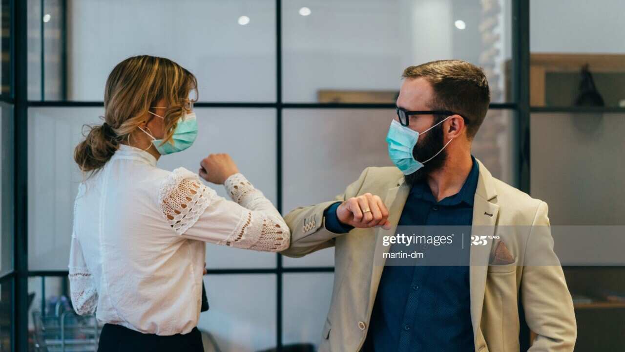 Colleagues in the office practicing alternative greeting for safety and protection during COVID-19 - Getty