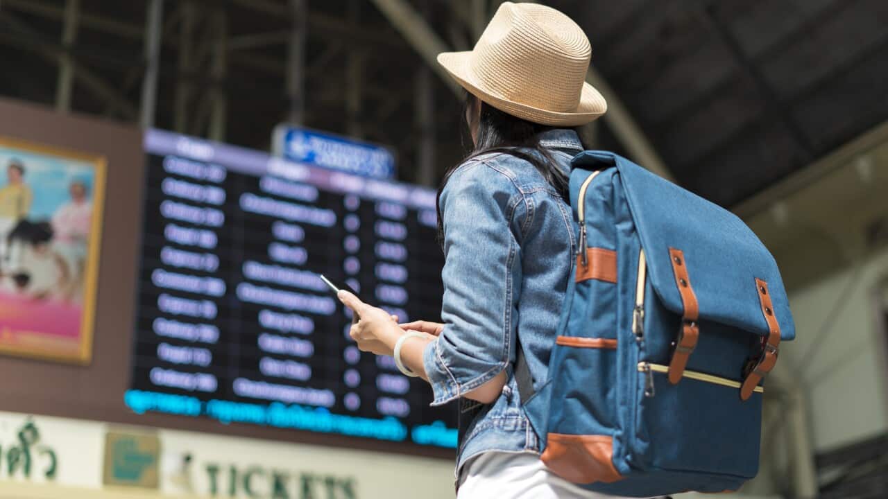 Young woman checking her train in timetable board