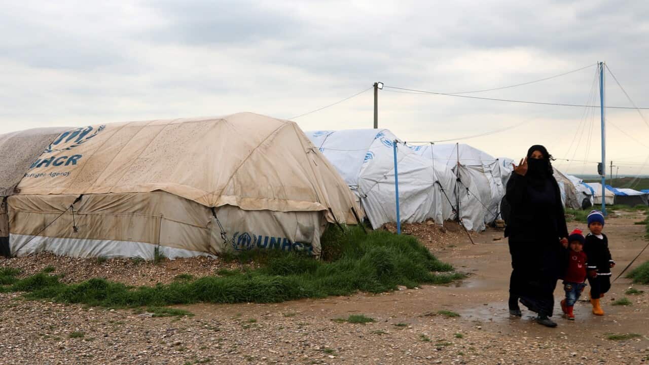 An unidentified woman, reportedly a wife of a suspected IS fighter, walks with her children at the Roj refugee camp in Hasakah, northeast of Syria, 30 March 2019