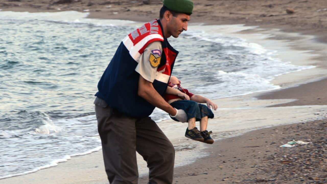 File image of toddler Alan Kurdi being carried to land by a Turkish policeman. (AAP)