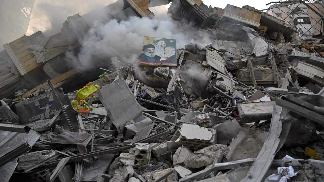 The ruins of a building, with a poster amidst the debris.