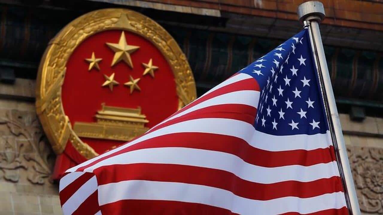 US flag flying with China national emblem as background