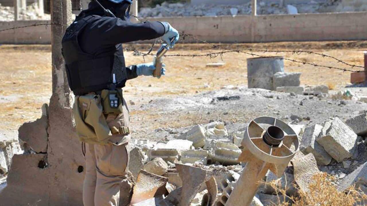A member of the UN investigative team takes samples of sand