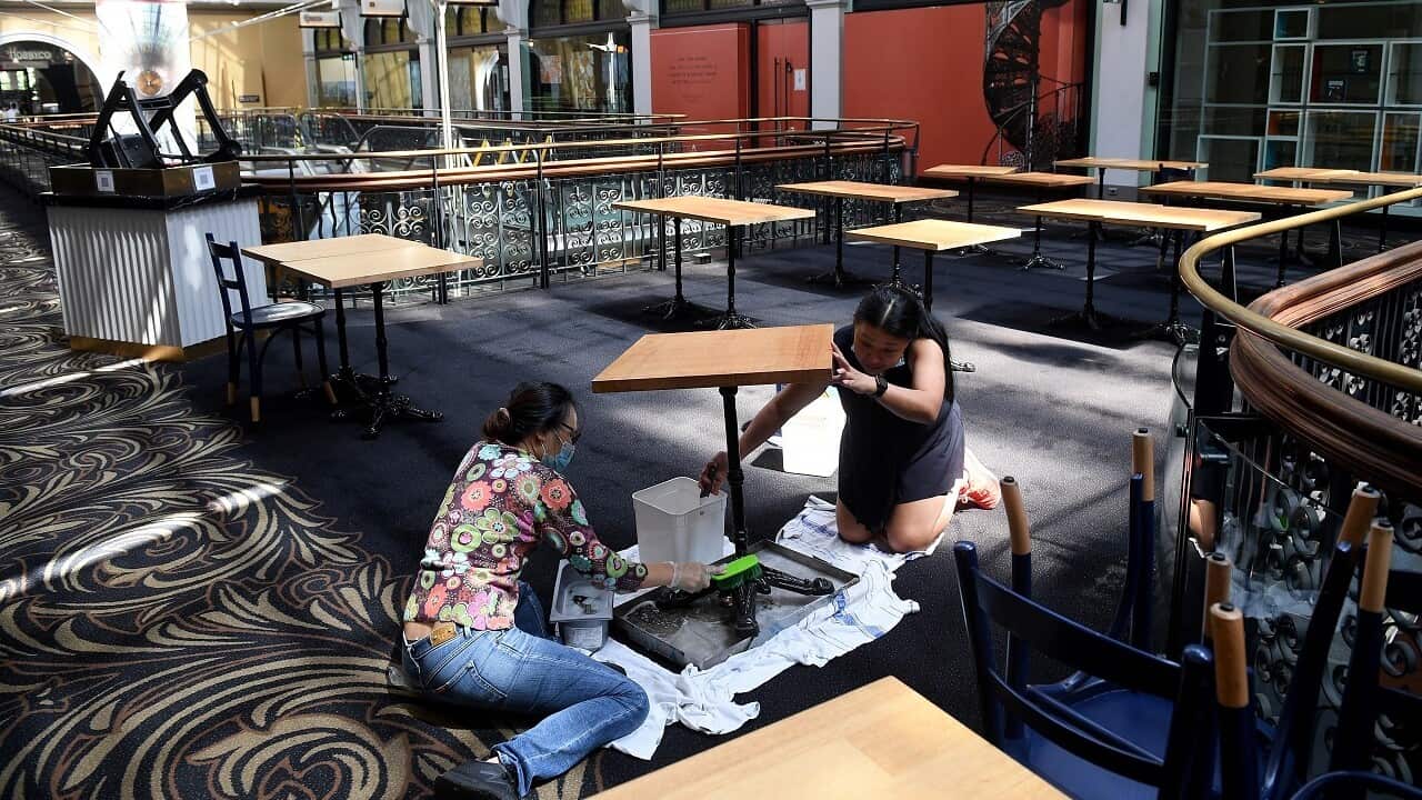 Staff prepare empty cafe seating areas for reopening, at the QVB in Sydney