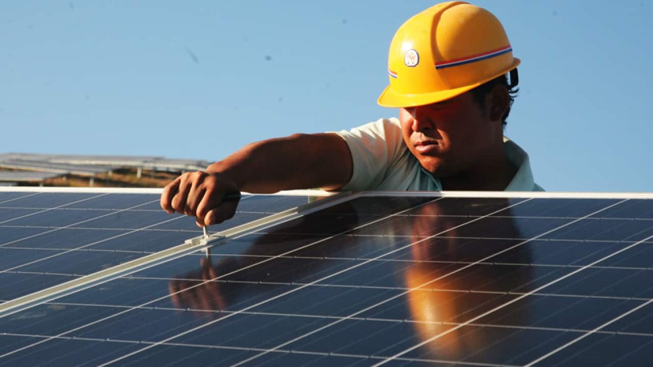 A worker installs solar panels.