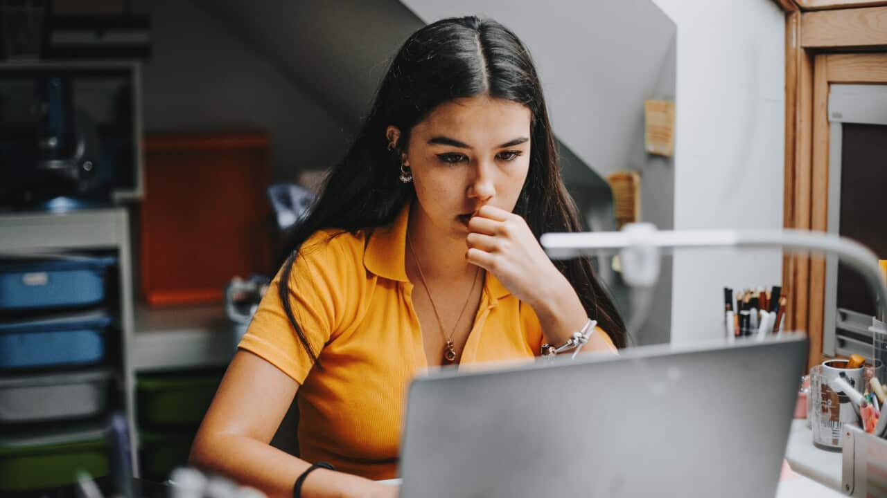 hispanic college student doing some home works from home with laptop