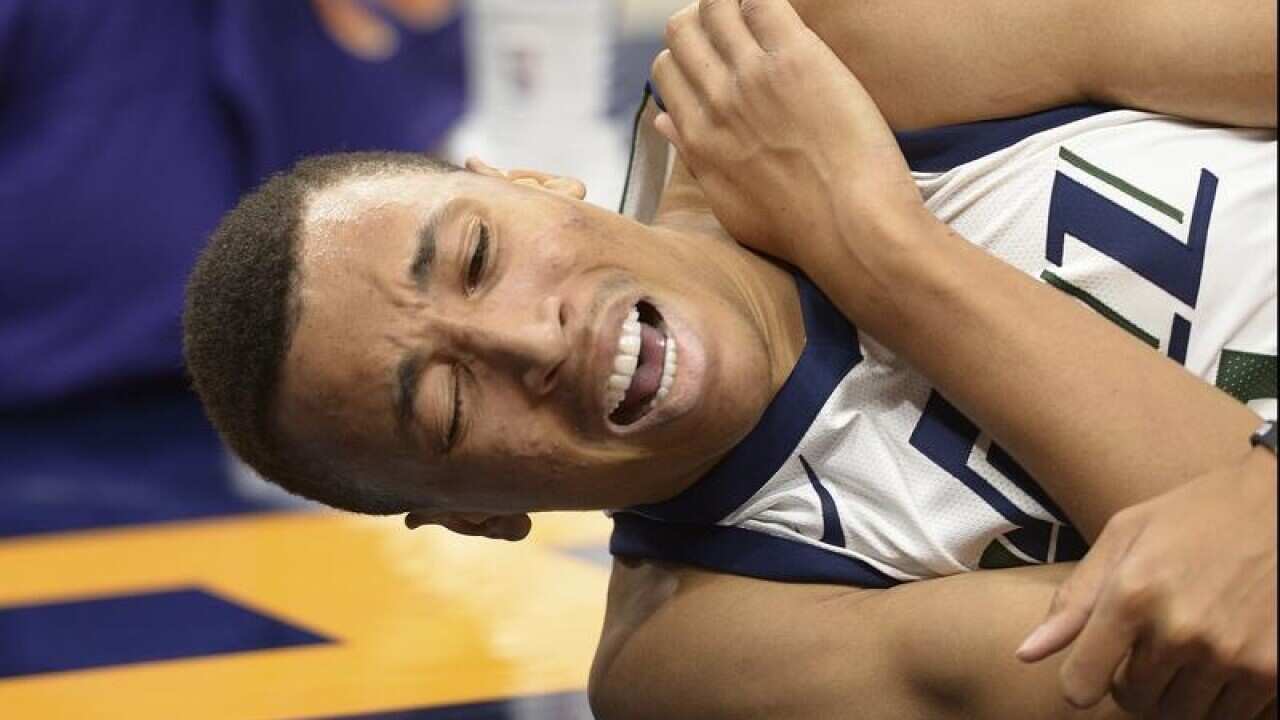 Utah Jazz guard Dante Exum grimaces as he grabs his left shoulder.