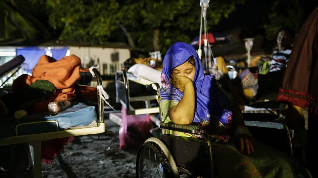 An Indonesian earthquake survivor rests as she gets medical treatment outside a military hospital in Palu, Central Sulawes.