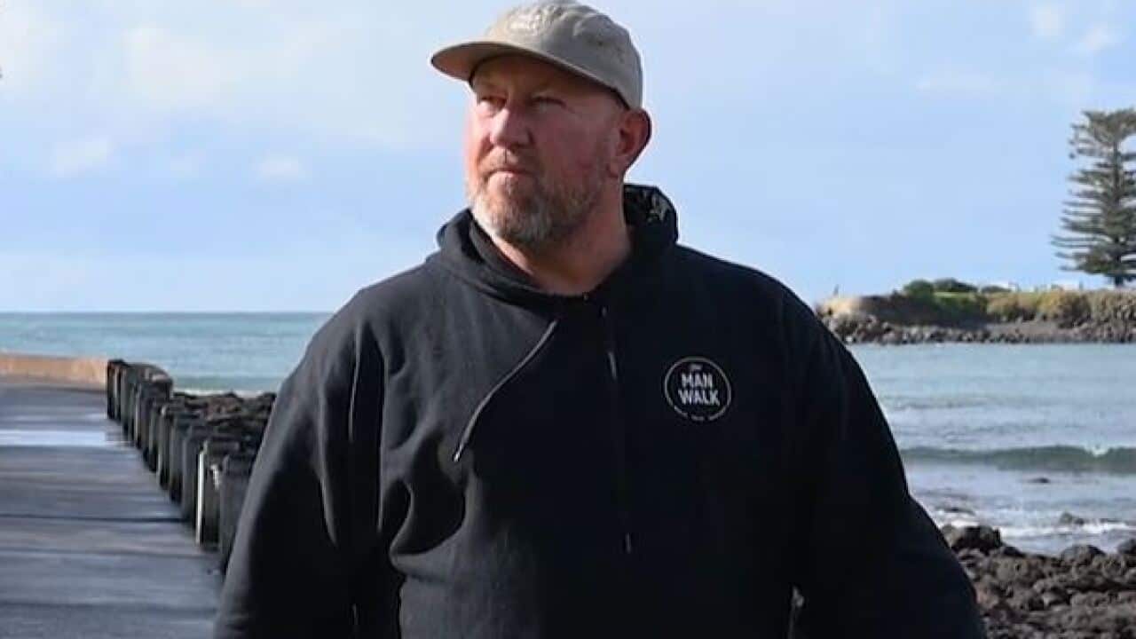 A man in a black hoodie on a coastal walk