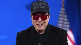 A man wearing all black, in hat that reads 'make America great again' and sunglasses smiling