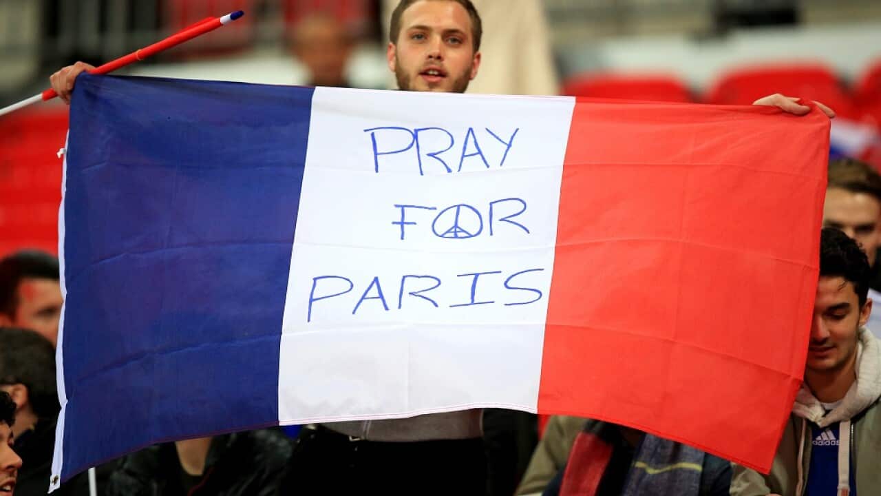 A fan holds a french flag reading "Pray for Paris